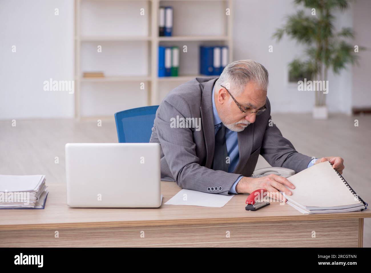 Old employee sitting at workplace Stock Photo