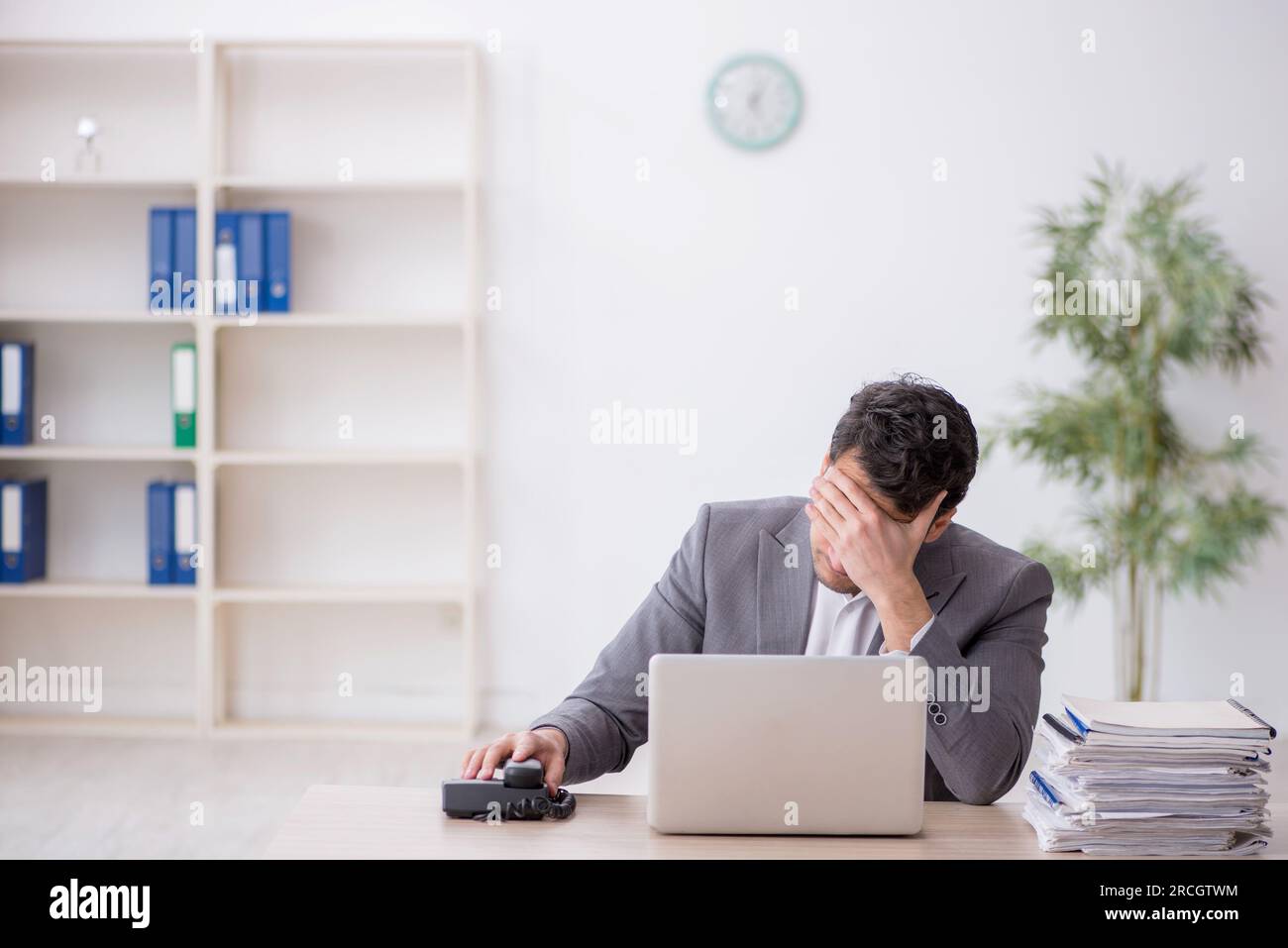 Young employee and too much work at workplace Stock Photo