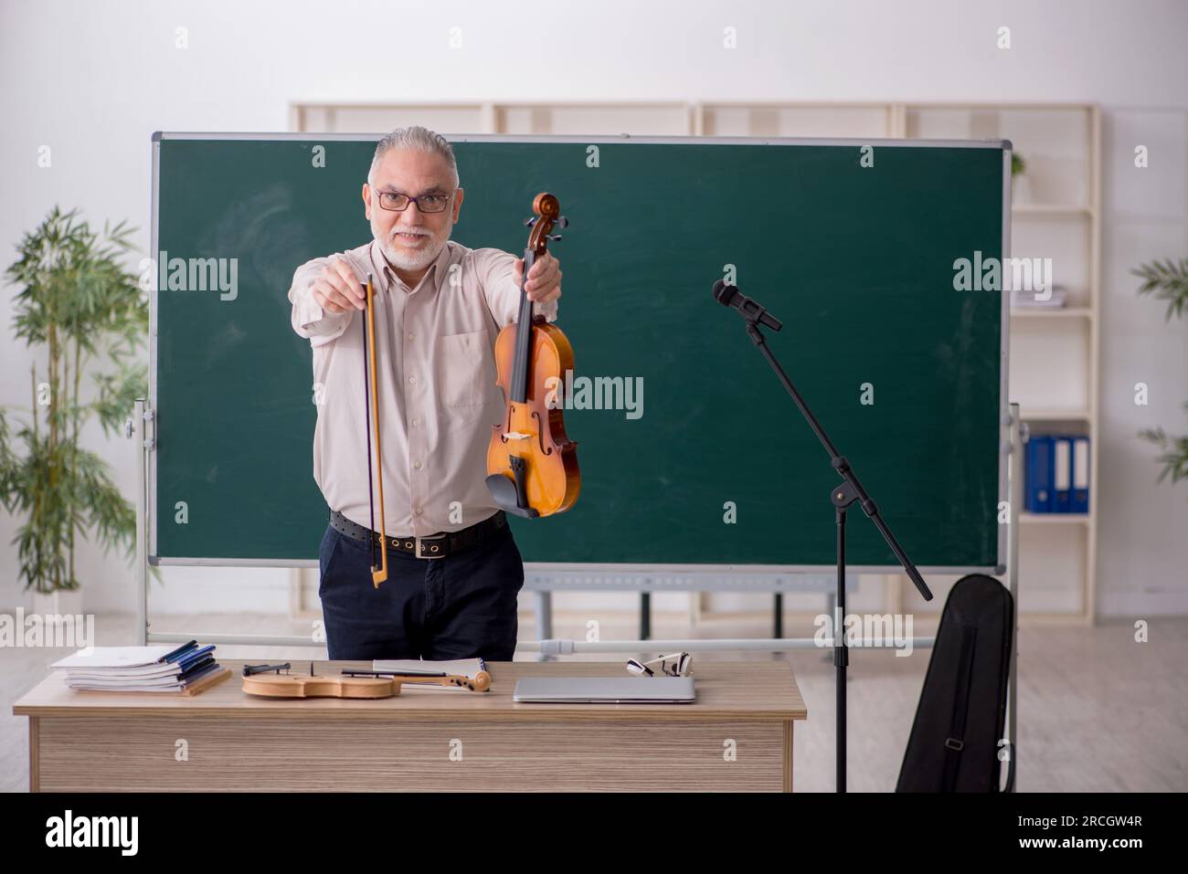 Old teacher playing violin in the classroom Stock Photo