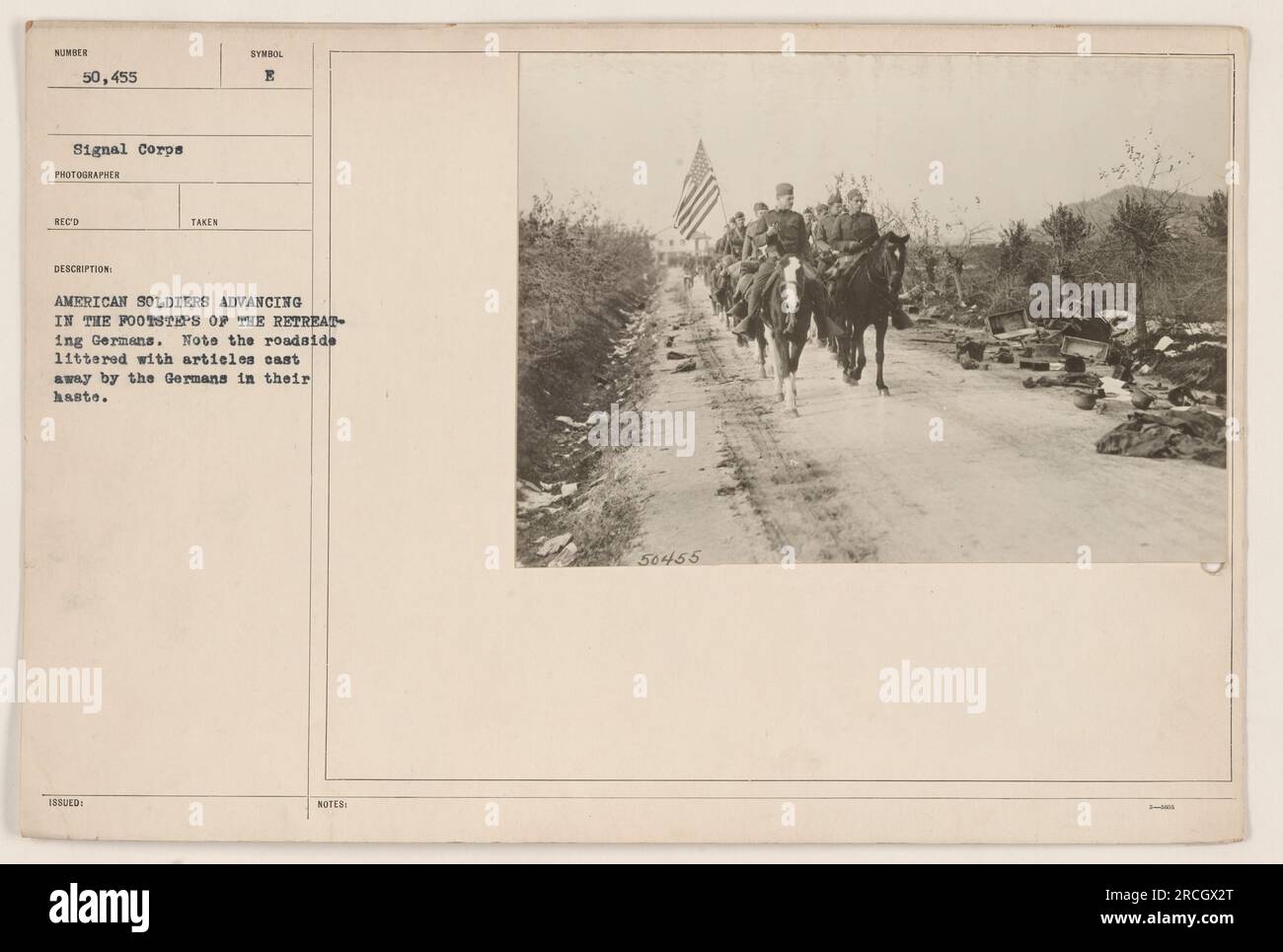 American soldiers advancing and following the retreating Germans. The roadside is seen littered with discarded articles left behind by the Germans in their hurry. The photograph was taken as part of the Signal Corps collection, with the assigned number 50,455. Description, issuance, and capture details are available. Stock Photo