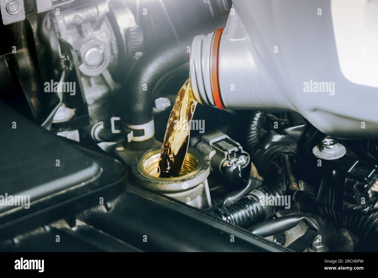 Close up of a bottle of motor oil being poured into a car combustion