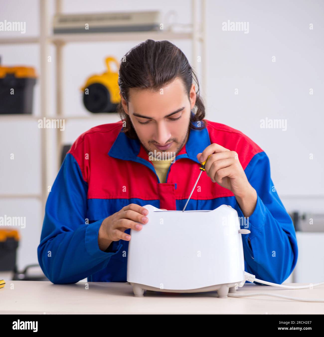 The young male contractor repairing toaster at workshop Stock Photo