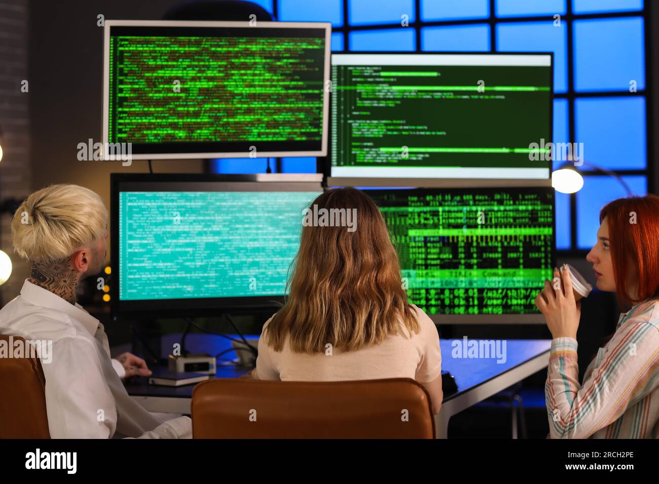 Team of young programmers working in office at night, back view Stock Photo