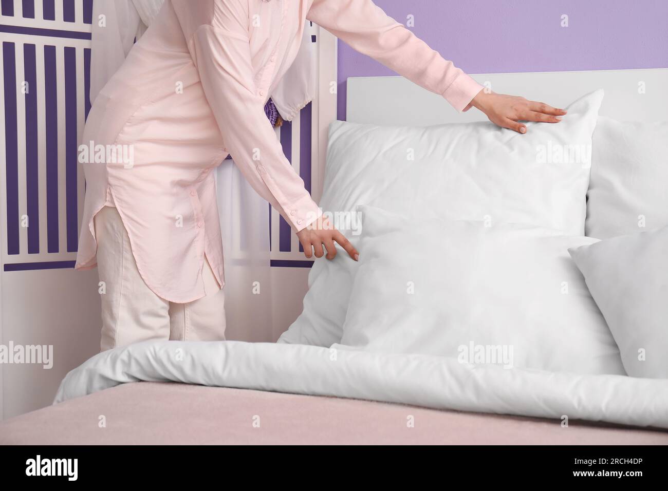 Woman in pajamas making bed at home Stock Photo - Alamy