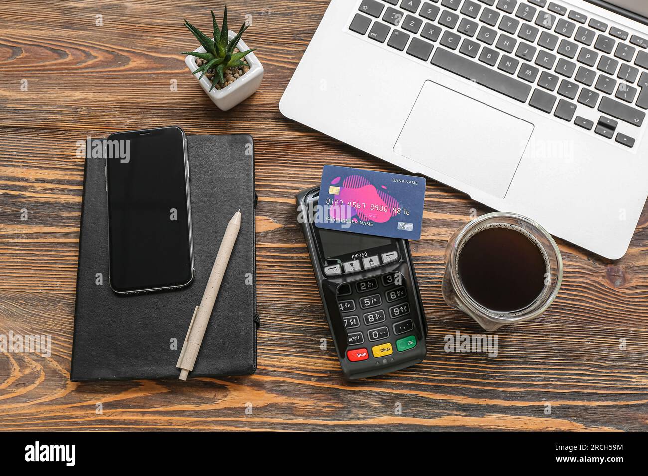Laptop with payment terminal, cup of coffee and credit cards on brown wooden background Stock Photo