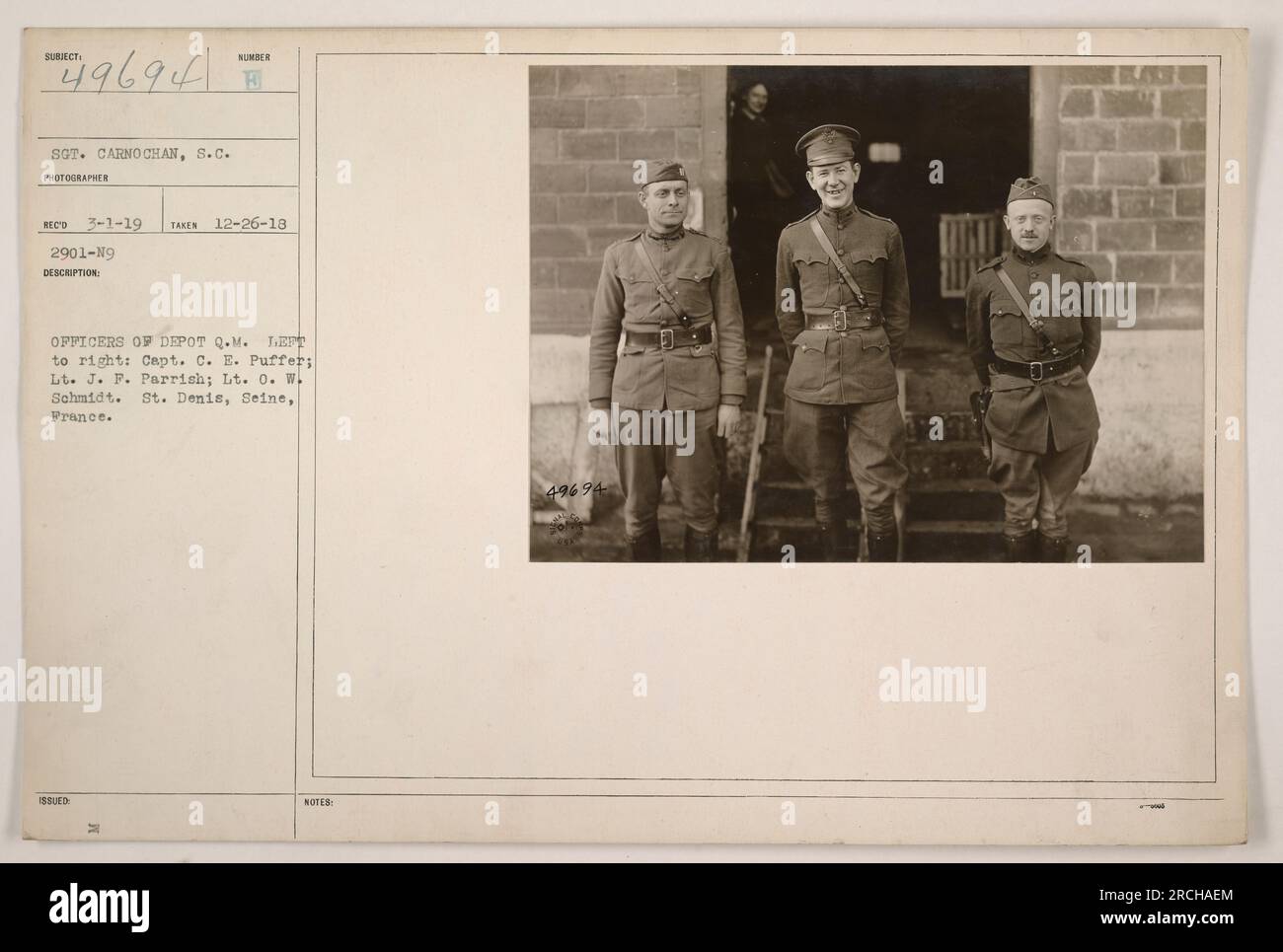 The photograph shows three officers of Depot Q.M. in St. Denis, Seine, France during World War One. The officers from left to right are Capt. C.E. Puffer, Lt. J.F. Parrish, and Lt. O.W. Schmidt. The photo was taken on December 26, 1918, by Sergeant Carno Chan. Stock Photo