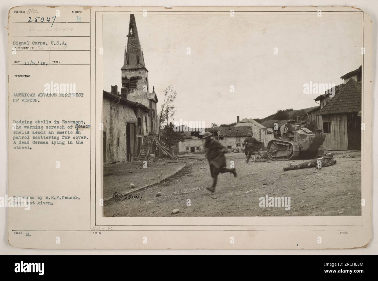 American patrol taking cover from shellfire in Exermont during the U.S. advance northwest of Verdun during World War One. A dead German soldier can be seen lying in the street. This photograph was released by the A.E.P. Censor, but the specific date of the image is unknown. Stock Photo