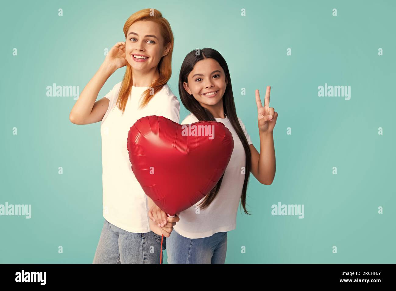 Valentines day. Smiling mother and daughter holding love heart balloon on blue background. Happy Valentines day to my mom. Stock Photo