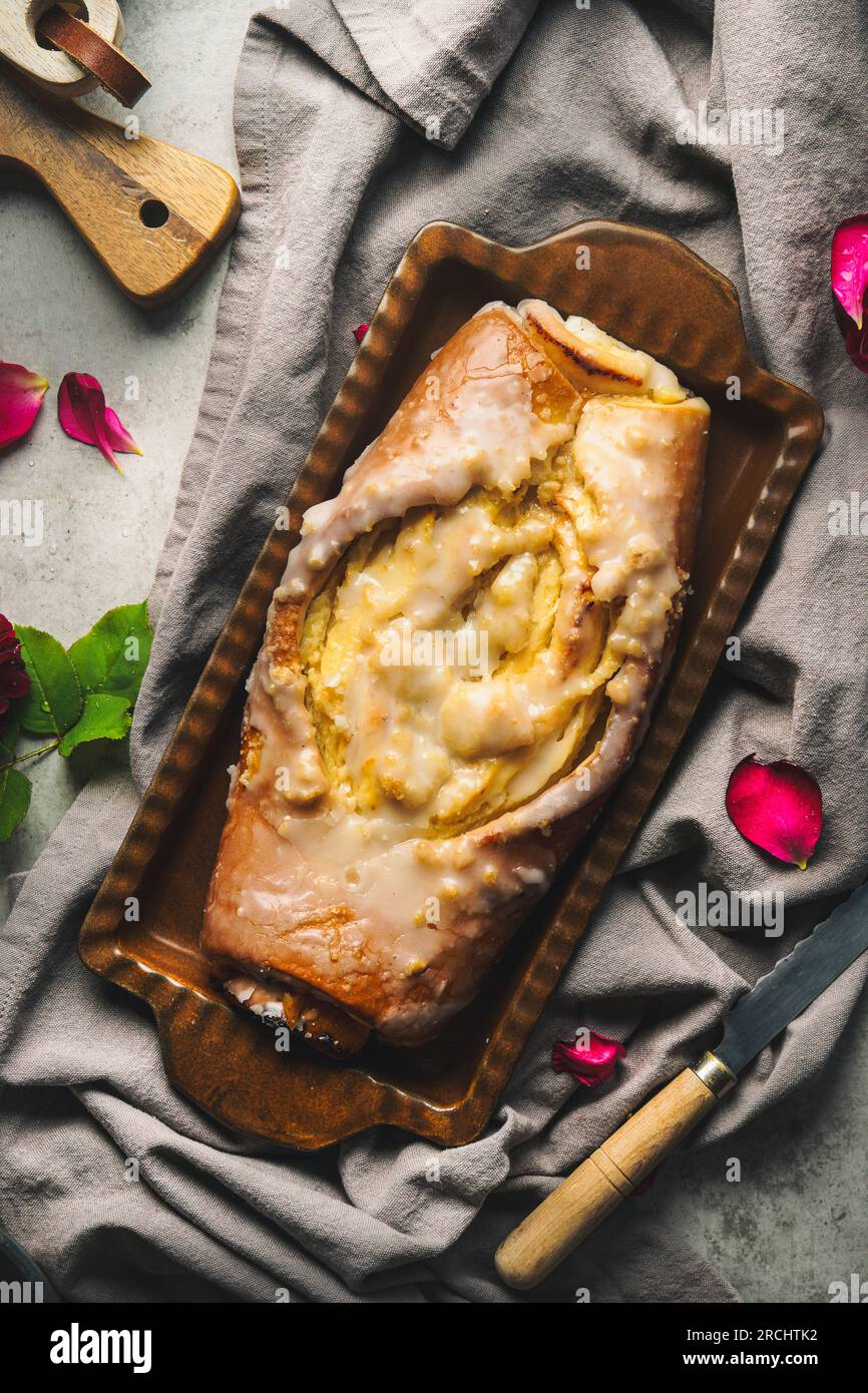 Delicious homemade babka cake on draped fabric with rose petals, top view Stock Photo