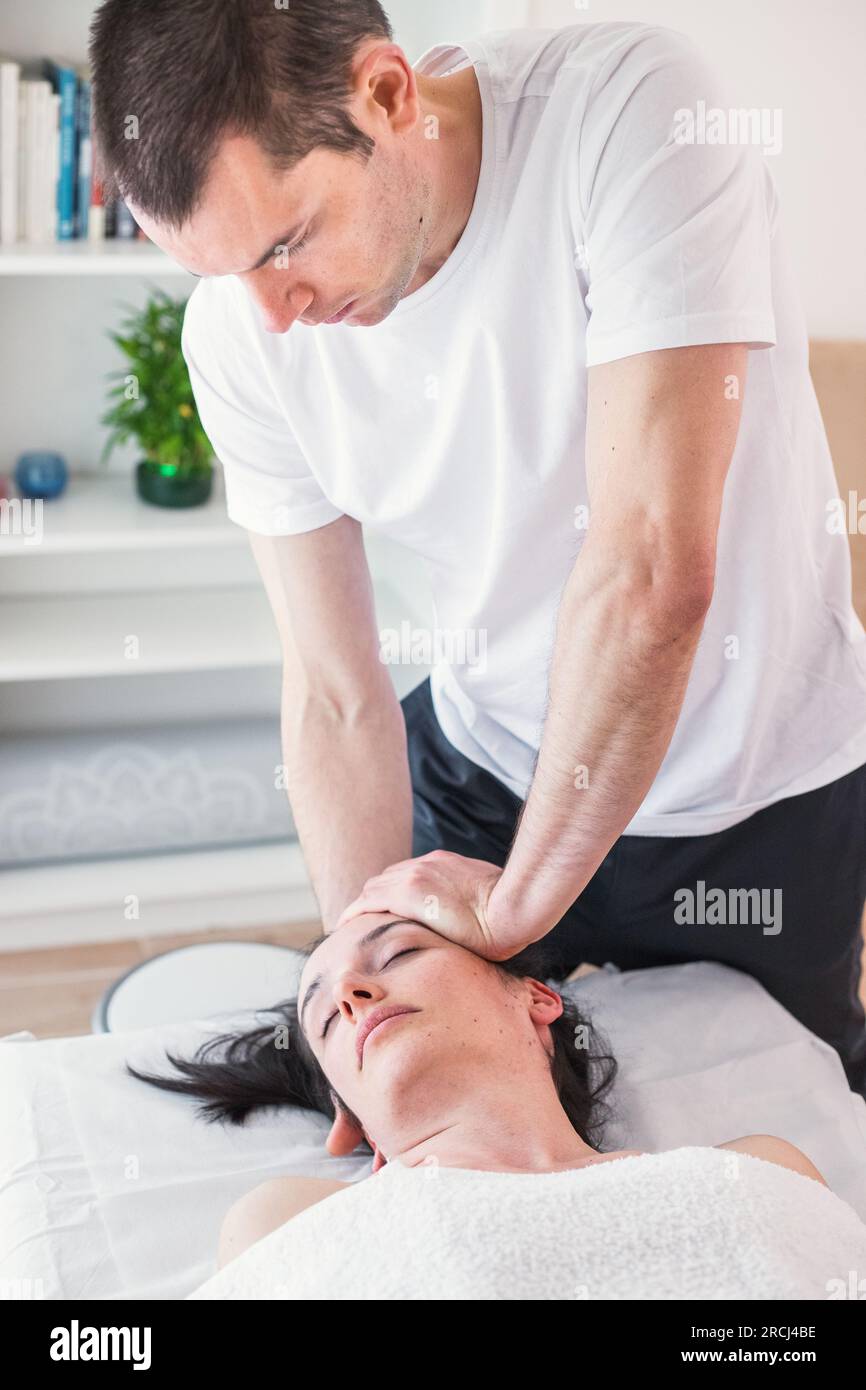 Therapist doing a session with localized massage in the region of the skull with the application of small, gentle pressures. CranioSacral Therapy. Stock Photo