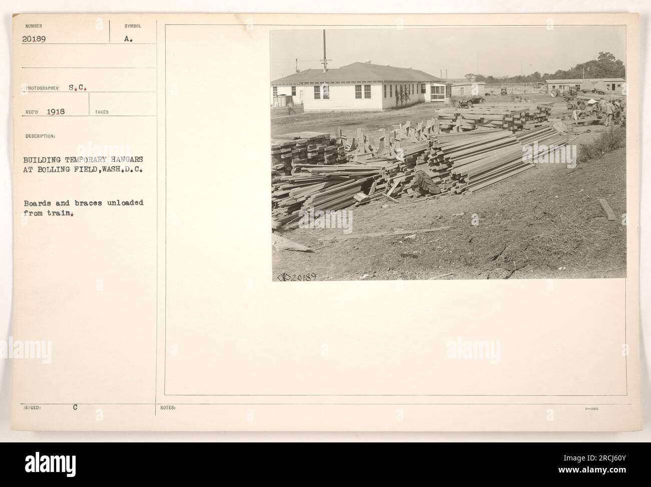 Construction work underway at Bolling Field in Washington D.C. Temporary hangars being built by American military during World War One. Boards and braces being unloaded from a train to assist in the construction process. (Note: Image 20189 from the series of photographs documenting American military activities during this time) Stock Photo