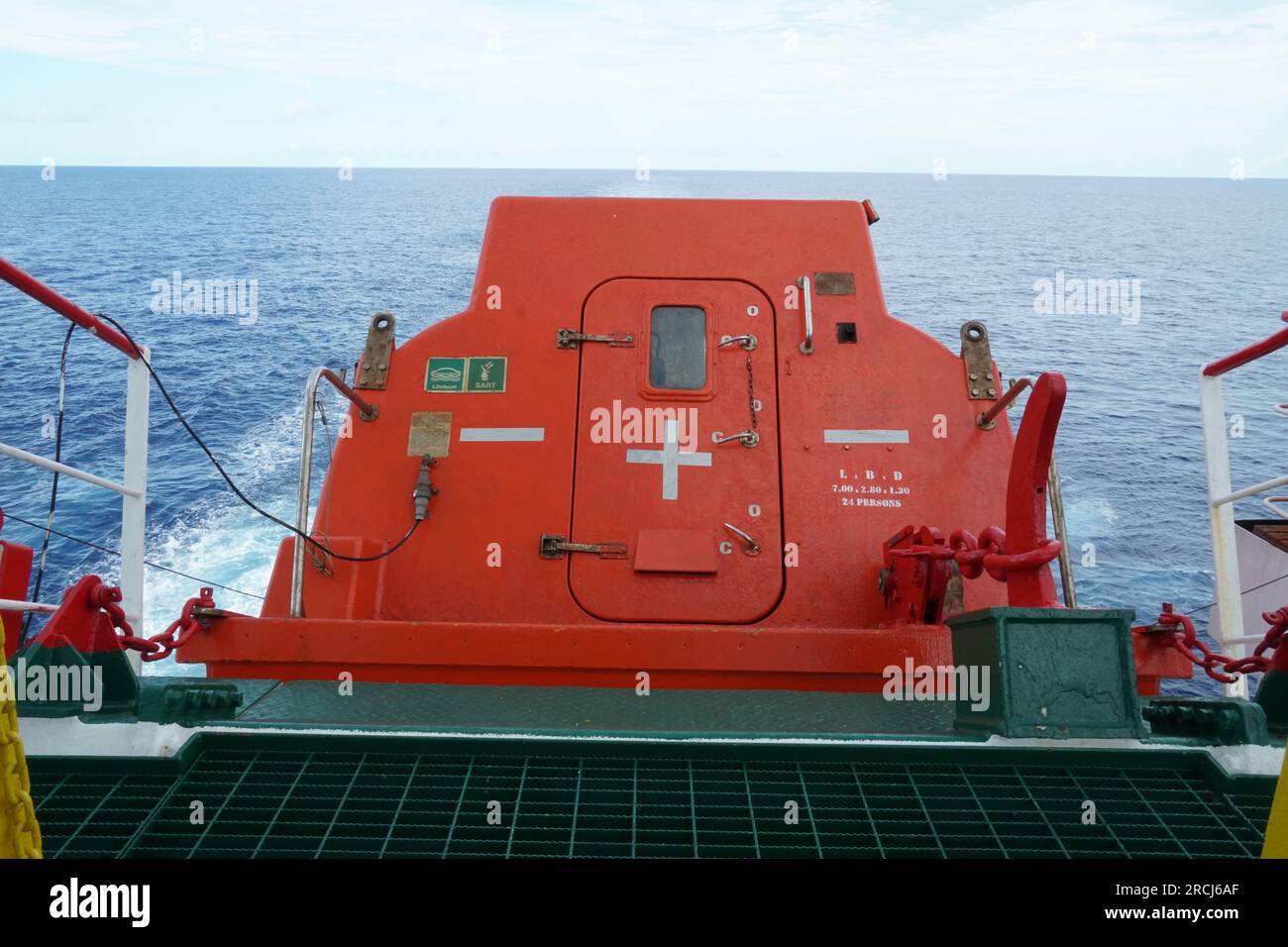 Aft of orange free fall lifeboat with door secured on launching ramp and ready to launch and abandon ship. Stock Photo