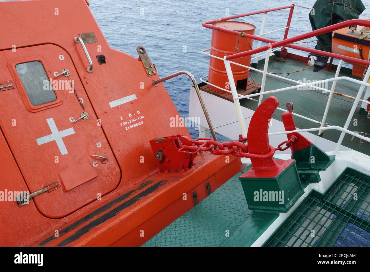 View on release mechanism of orange free fall lifeboat with hook and chain secured on launching ramp. Stock Photo