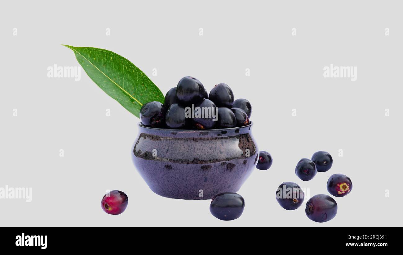 Organic jamun or jambolan with green leaf in a ceramic bowl on white background. Healthy food concept. Stock Photo