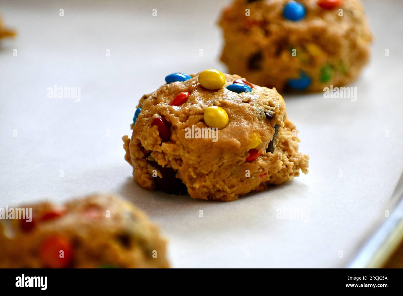 Monster cookie dough on a parchment paper lined baking sheet Stock