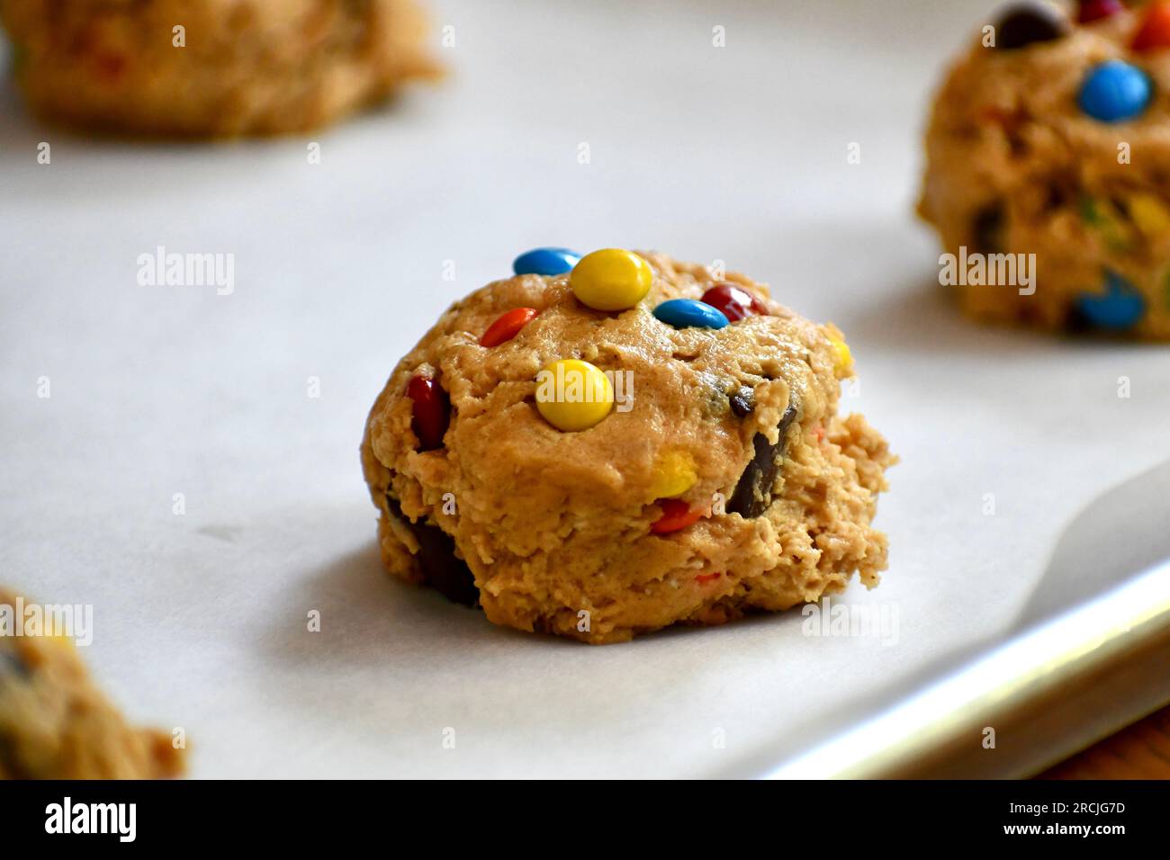 Monster cookie dough on a parchment paper lined baking sheet Stock