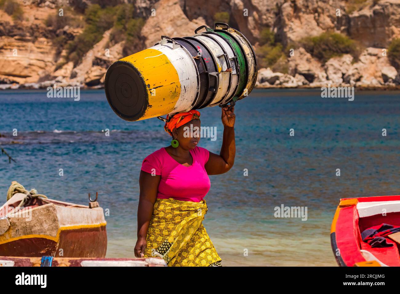 A woman carries some empty vats effortlessly on her head, Santiago Island, Cape Verde Islands in the Atlantic Ocean Stock Photo