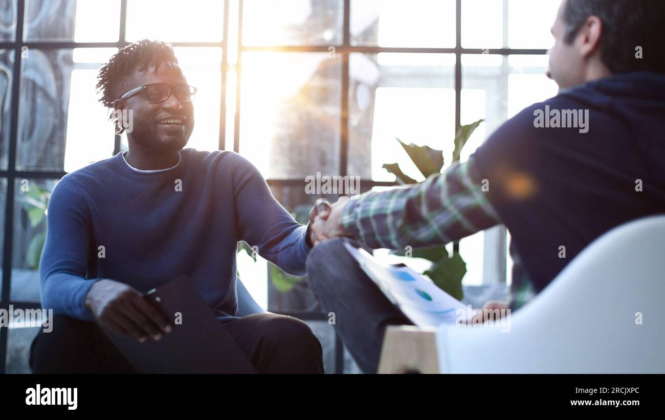 a black man with a folder in his hands shakes hands Stock Photo