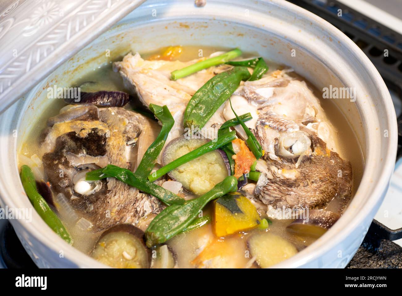 Fish head stew in a ceramic pot. Sinabawang ulo ng isda. Stock Photo