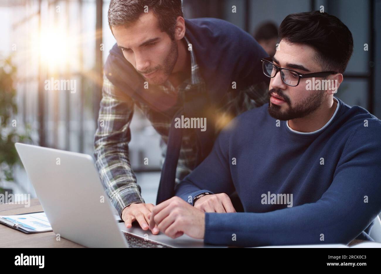 Two male colleagues are talking at the table in the office stock photo