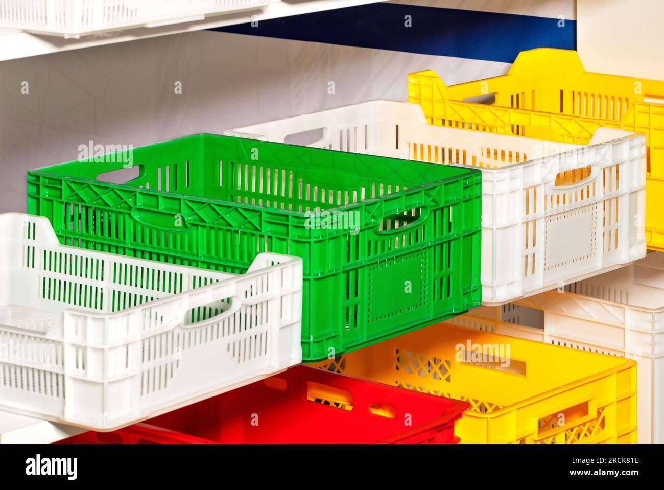 Plastic boxes in red, green, white and yellow colors on racks for storing various products Stock