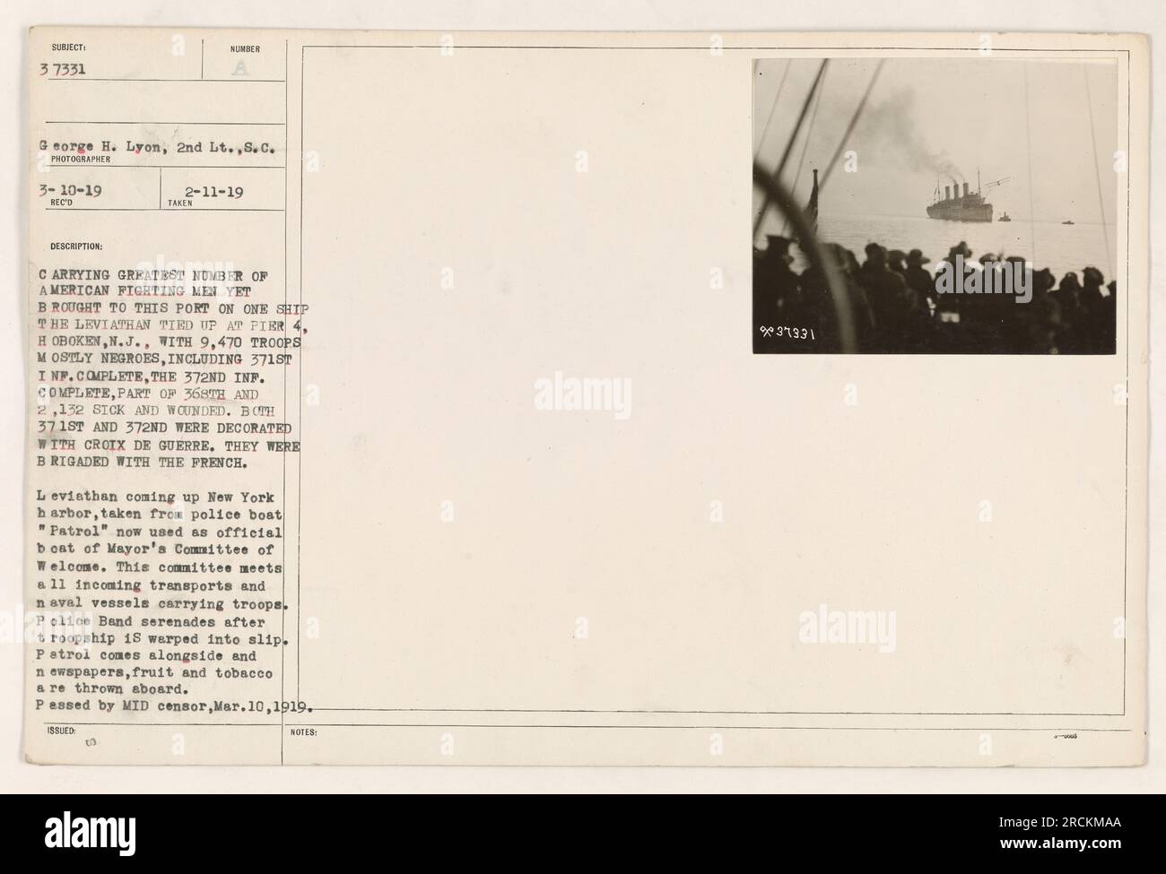 Title: American Fighting Men Aboard the Leviathan at Port Hoboken Caption: On March 10, 1919, Lieutenant George H. Lyon captured the image of the Leviathan carrying the largest number of American fighting men to arrive at Port Hoboken on a single ship. The troopship transported 9,470 troops, primarily comprised of African American soldiers including the 371st and 372nd Infantry and part of the 368th Infantry, along with 2,132 sick and wounded servicemen. The decorated 371st and 372nd Infantry were proudly brigaded with the French. This photo was taken from the police boat 'Patrol,' repurposed Stock Photo