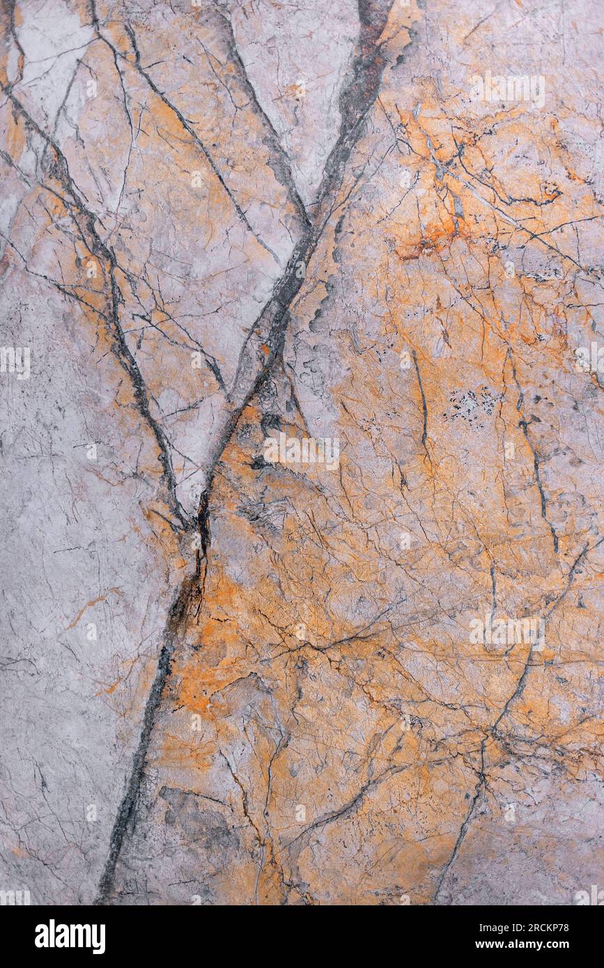 The marble surface with a pink-brown tint is covered with black cracks and spots. Vertical image. Stock Photo