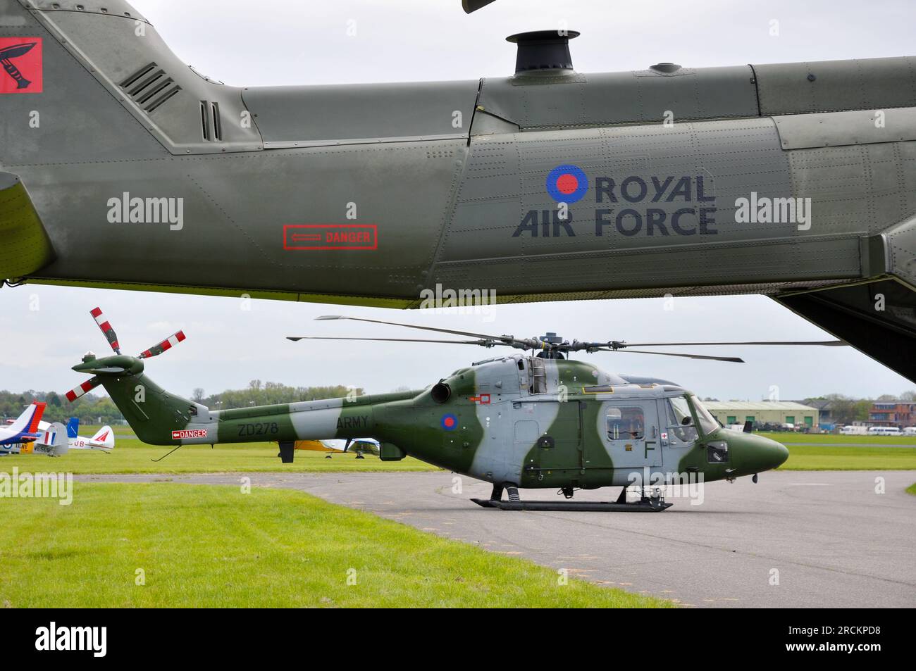 British Army Air Corps Westland WG-13 Lynx AH7 helicopter, framed by the tail of a Royal Air Force Merlin. Abingdon Airshow Stock Photo