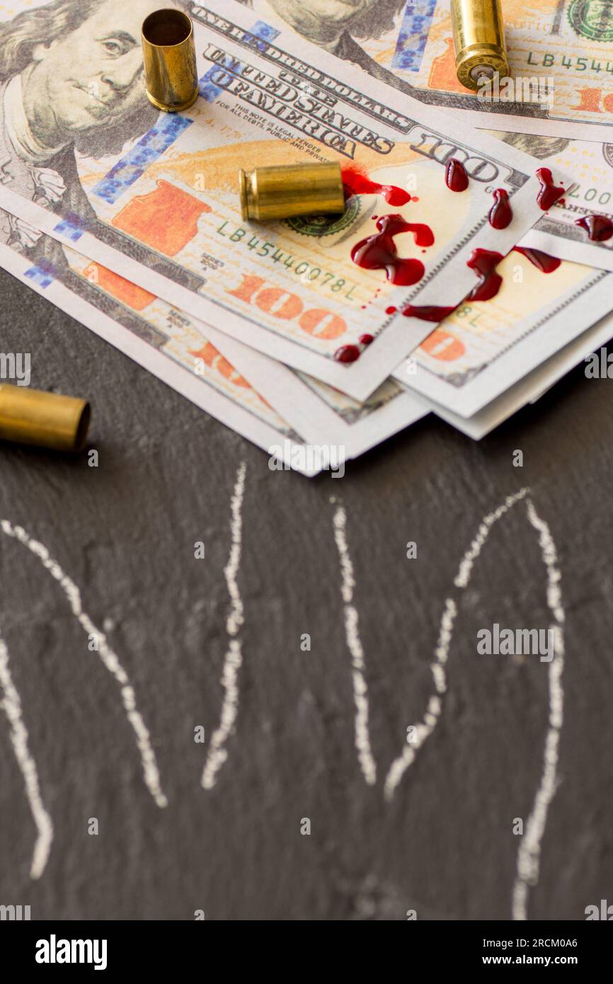 spat blood on hundred dollar bills and fire arm cartridges and body part outline crime scene dirty money concept Stock Photo
