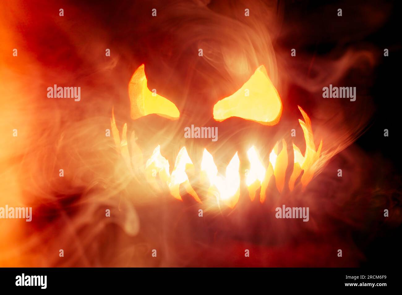 Scary Halloween jack o lantern face glowing in smoke and fire Stock ...