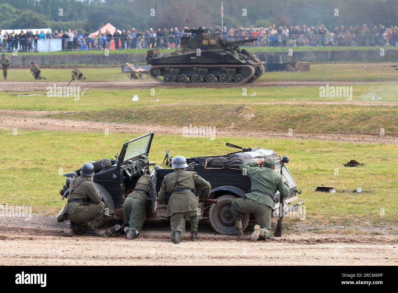 Historical reenactment of German Army soldiers behind a jeep with a tank in the background in the Tankfest main arena display at Bovington Tank Museum Stock Photo