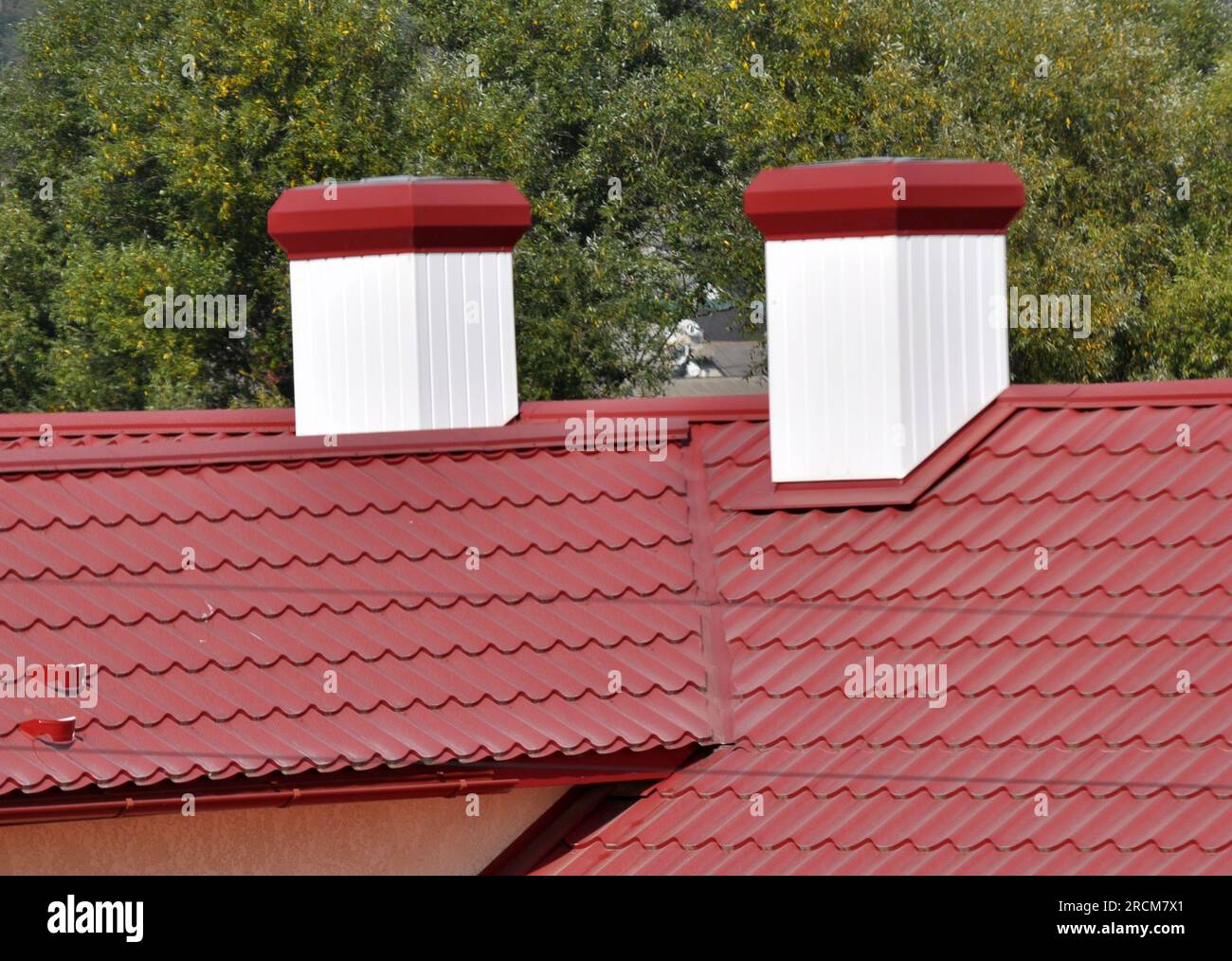 A chimney on the roof of a house covered with metal tiles or a metal