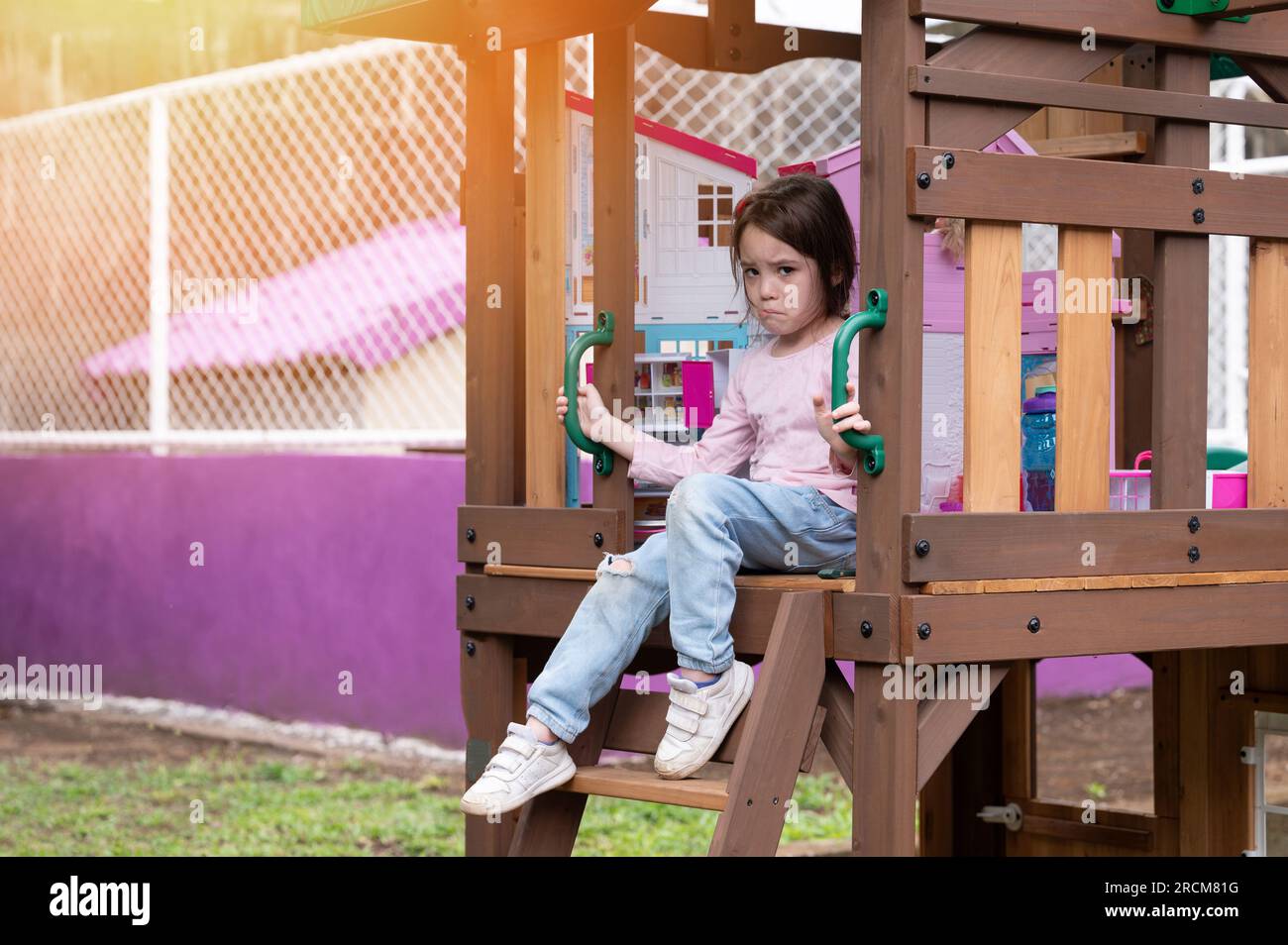 One kid girl sad sitting in playground background. Kid bulling theme Stock Photo