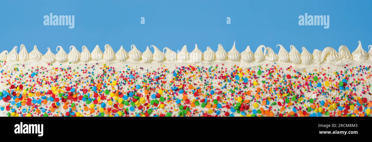 Birthday cake decorated with colorful rainbow sprinkles and white icing ...