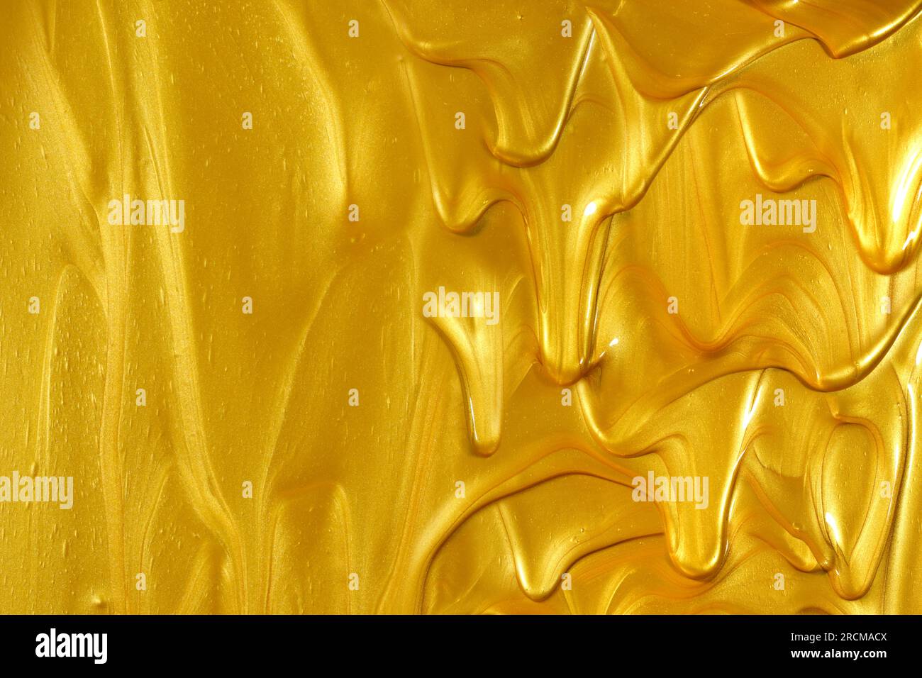 Glittering shiny metallic gold paint flowing and dripping downward