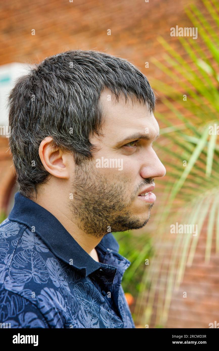 Caucasian young man unshaved profile view walking in the city , daytime Stock Photo
