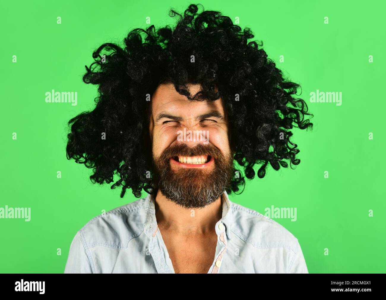Funny man in black wig. Man with beard and mustache in curly periwig. Bearded hipster in black curly afro wig. Barbershop. Stylish guy with black hair Stock Photo