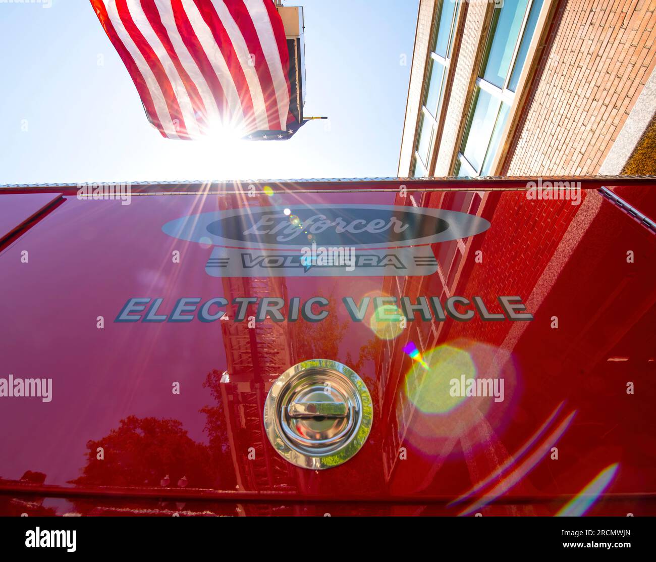 The sun bursts behind an American flag during the “Push In” ceremony placing the new electric fire engine” in service as Portland Fire Engine1. Stock Photo