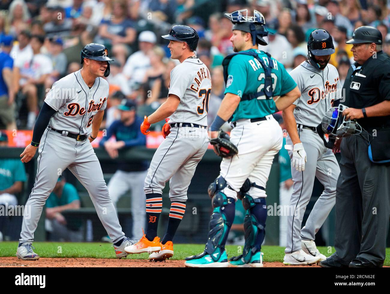Detroit Tigers' Spencer Torkelson, left, smiles after he and Riley Greene,  back right, scored on a three-run home run by Kerry Carpenter (30), while  Seattle Mariners catcher Cal Raleigh waits during the