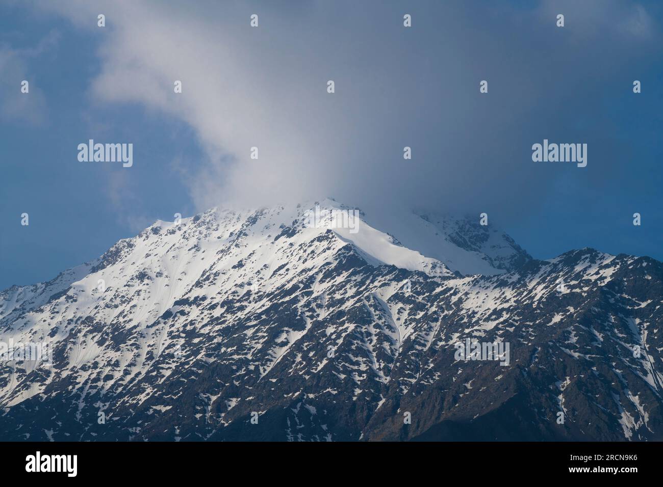 Snow covered mountain with peak hidden by a cloud. Northern Caucasus, Russia Stock Photo