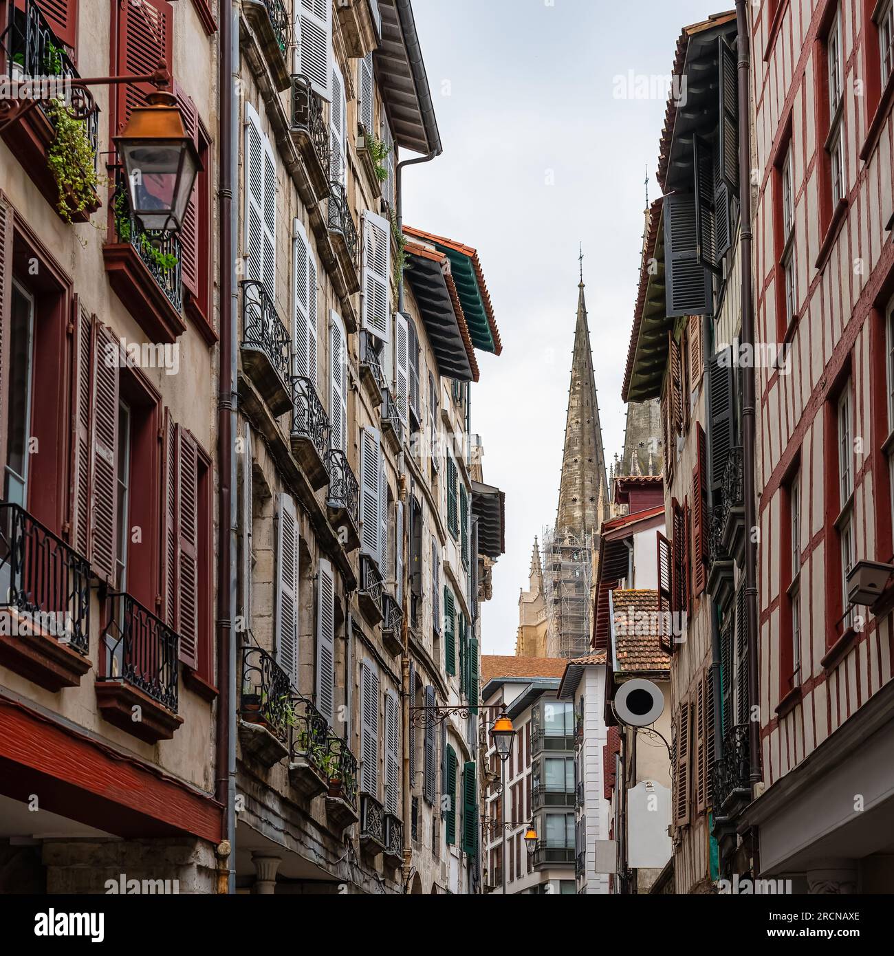 Calle con tipicas casas con la torre de la catedral de Bayona al fondo, Francia. Stock Photo