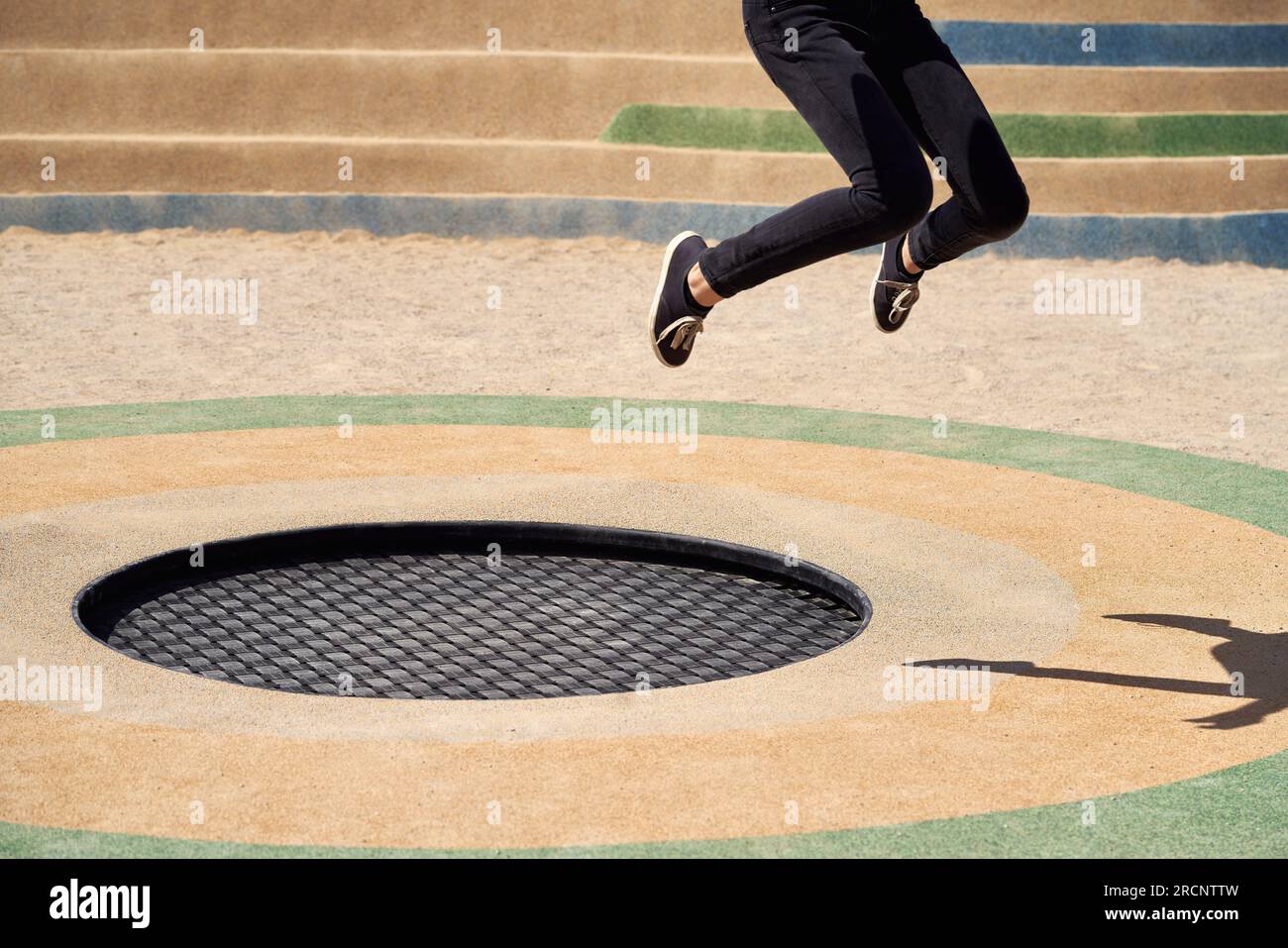 Black trampoline outdoors, with legs of a teenage girl jumping on it Stock Photo Alamy