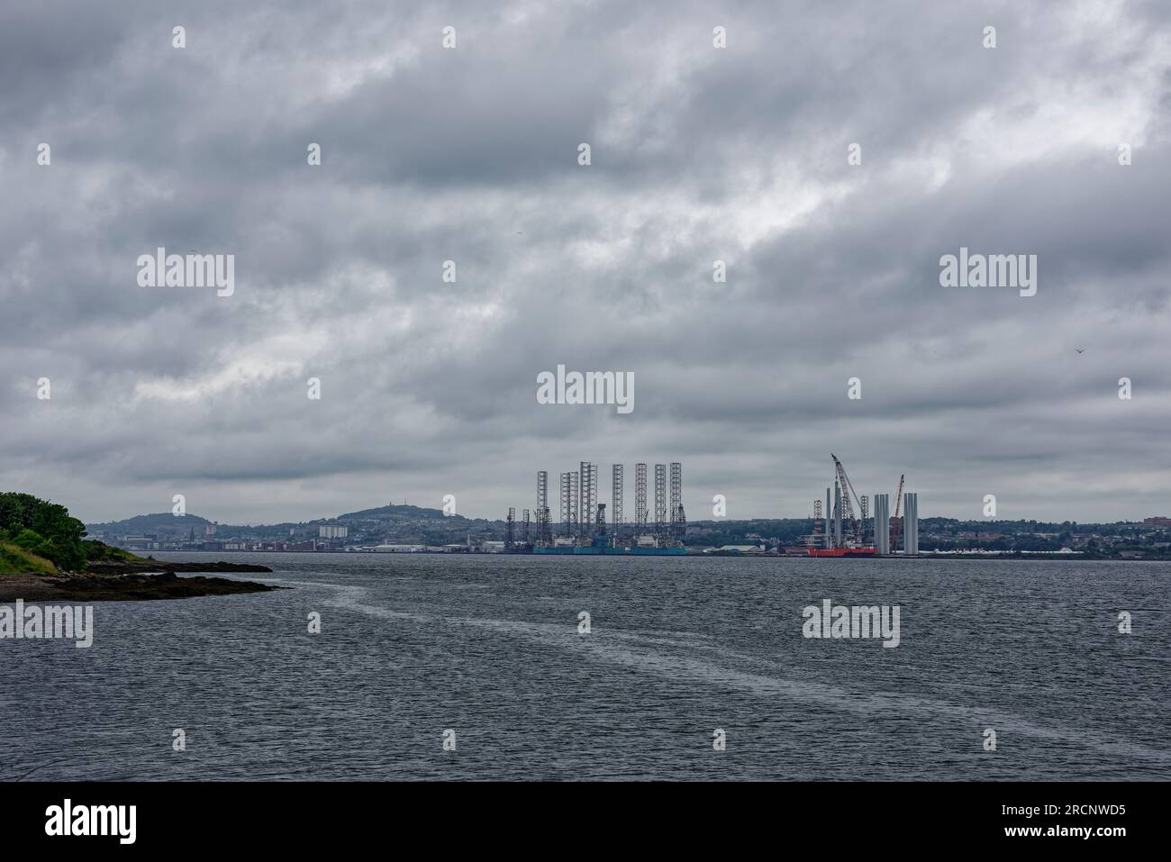 The view of the Port of Dundee from Tayport the other side of the Tay Estuary on a dark Rainy day in July with Oil Rigs lining the Wharfs of the Port. Stock Photo