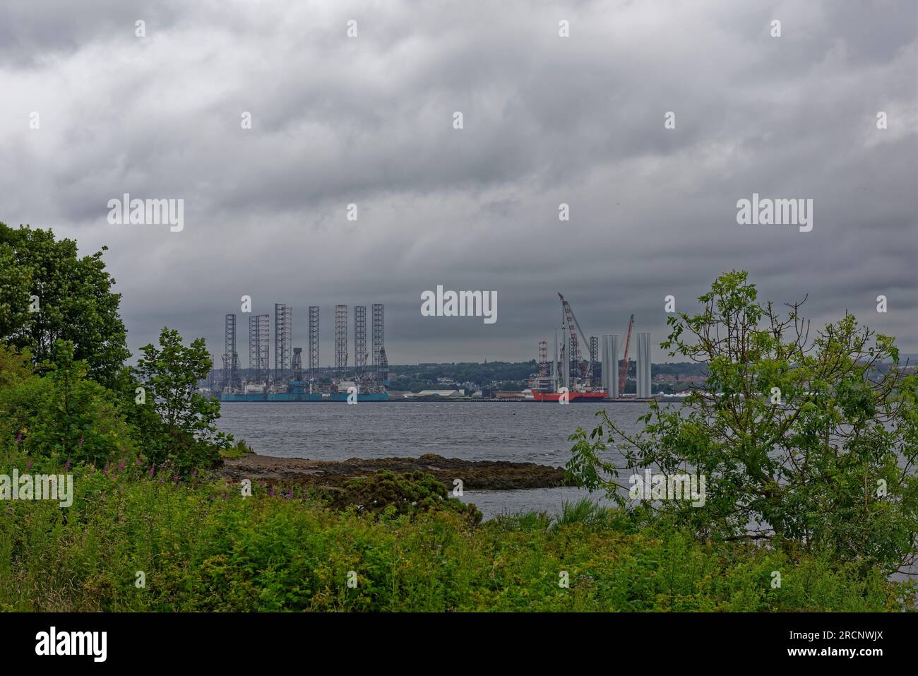 Jack Up Oil Rigs and the Fred Olsen Windcarrier Vessel alongside the Port of Dundee with Wind Turbines being made ready for transportation. Stock Photo