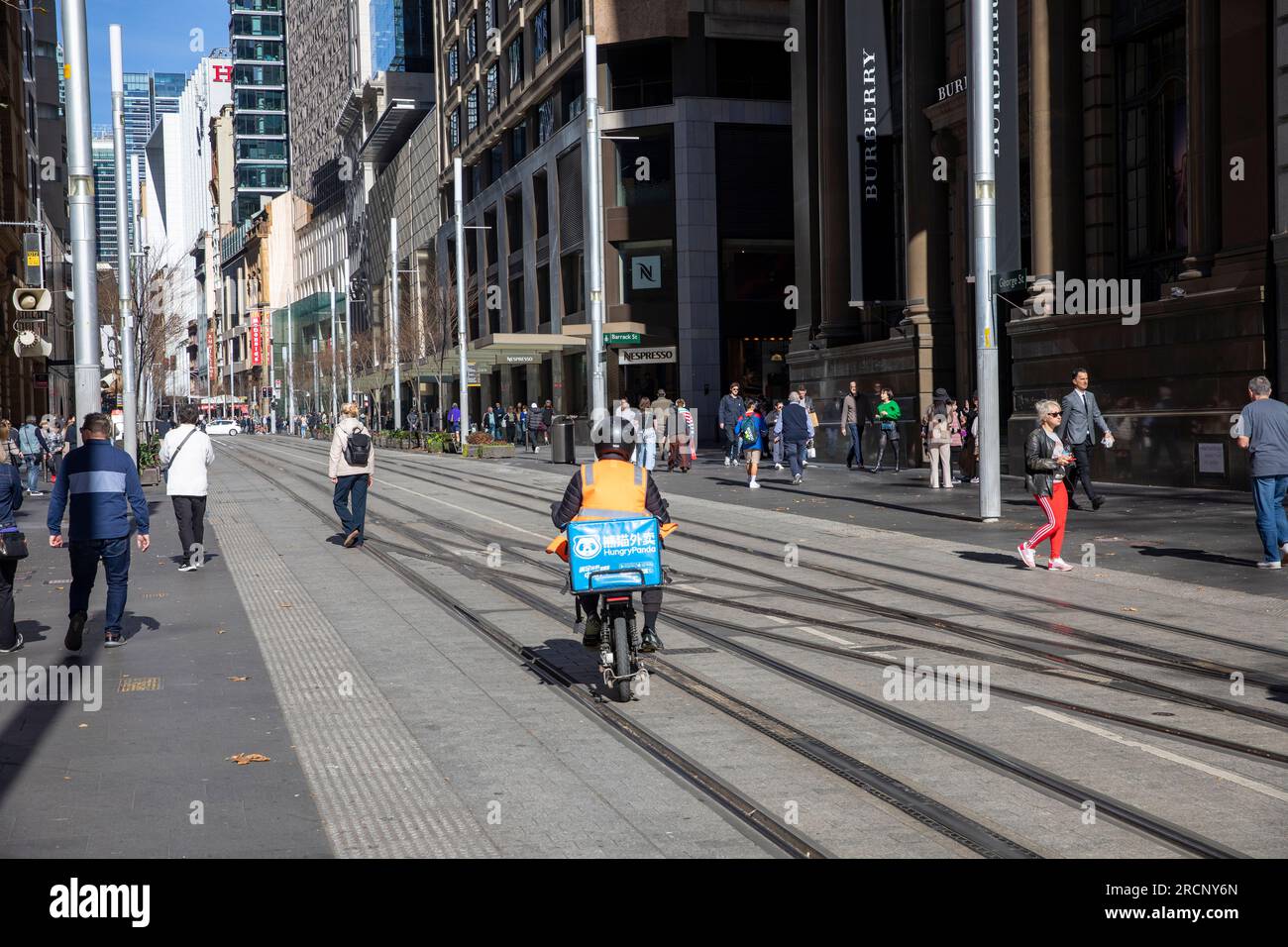 George street Sydney city centre, food delivery cyclist rides along the CBD light rail tracks,Sydney,NSW,Australia Stock Photo