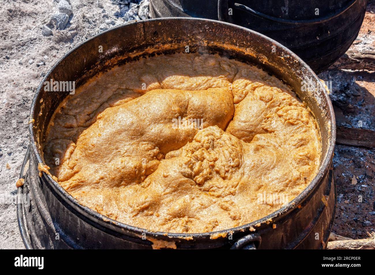 African cooking outdoors ,huge pot of porridge pap in a cast iron pot Stock Photo