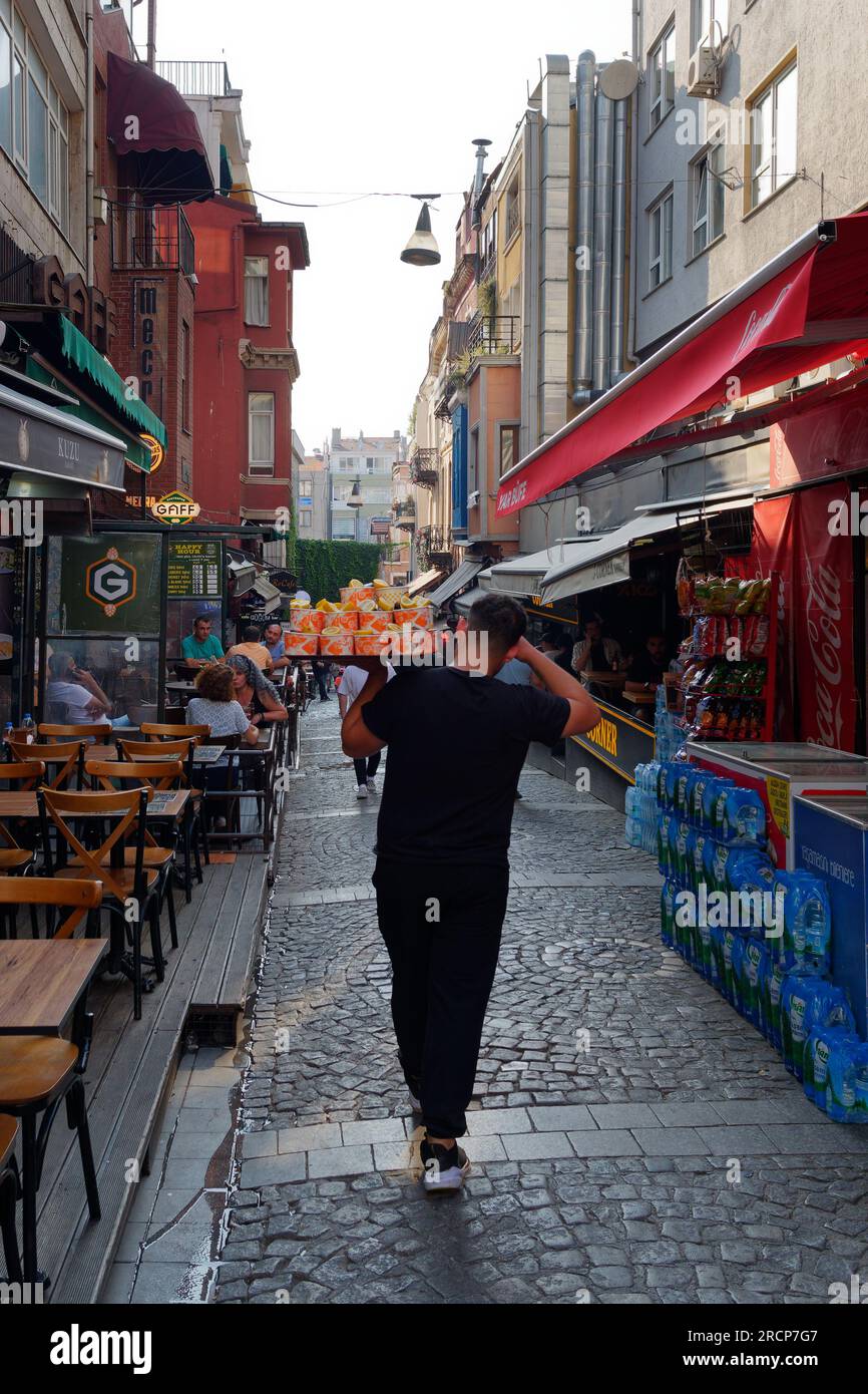 Waiter carries a tray on a street full of cafes and restaurants in the Kadikoy neighbourhood on the Asian side of Istanbul, Turkey Stock Photo