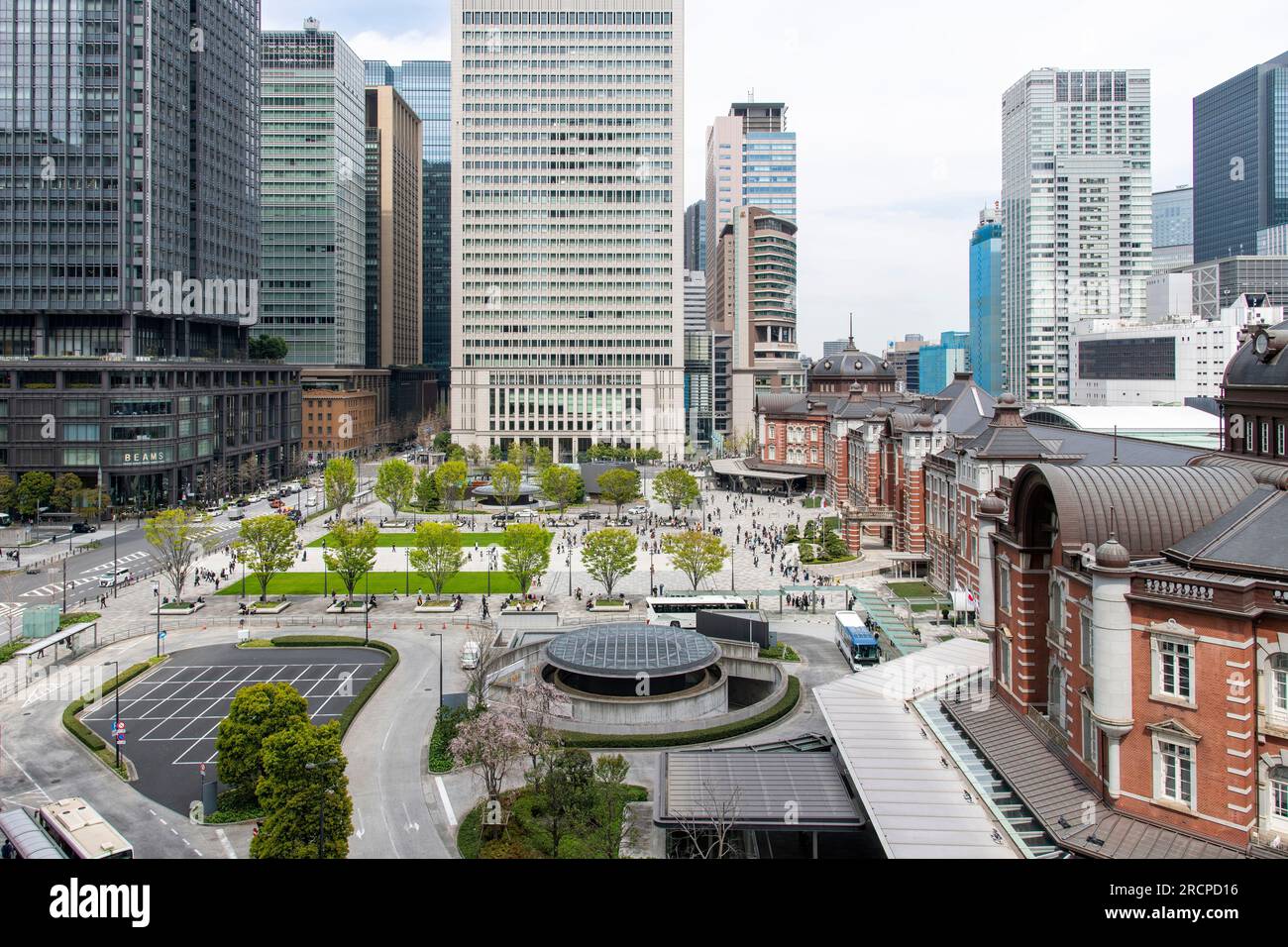 Tokyo, Japan-April 2023; High angle view over the Marunouchi Ekimae square, granite-paved with lawns and surrounding skyscrapers bordering the red-bri Stock Photo