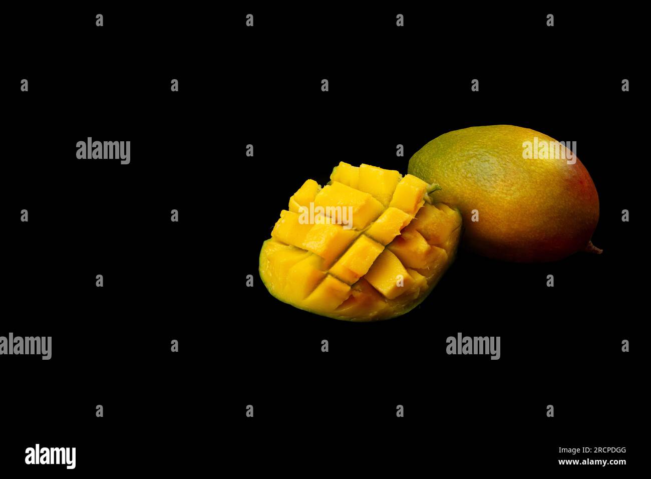 Whole mango fruit and sliced half of mango isolated on black background
