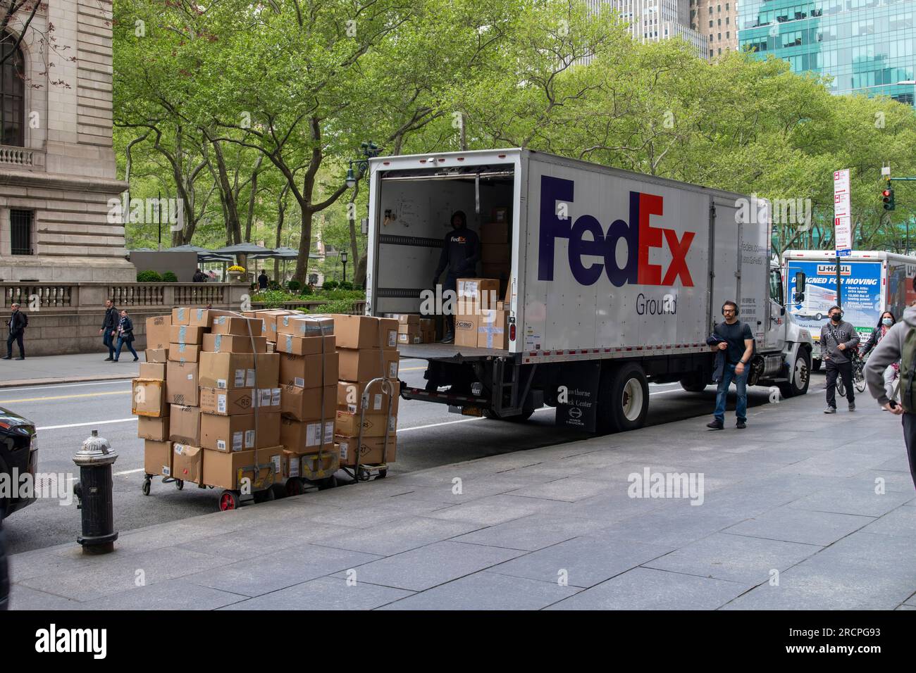 New York City, NY, USA-May 2022; View of a FedEx Ground delivery truck parked on W42nd Street opposite Bryant Park with delivery cart stacked with par Stock Photo